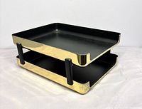 Oblique view showing polished brass exterior, black enamel interiors, and two black supports