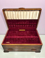 Chest open showing maroon velvet utensil slots, white satin lid lining, Community Plate label