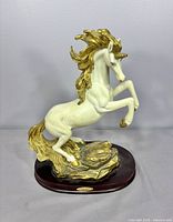 Front right view of white and gold resin unicorn on wood base