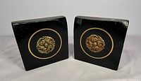 Front view of both bookends showing brass rosettes and black finish