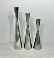Front view of three graduated aluminum candle holders