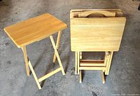 One TV tray open beside stacked trays on stand