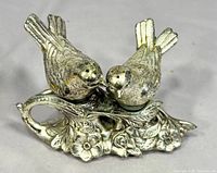 Front view of two silver-plated birds on ornate branch base