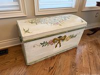 front view of painted storage chest showing floral and ribbon artwork