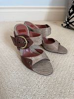 Three-quarter view of both sandals showing fabric uppers, leather trim, and buckle