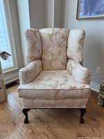 Front view of cream damask wingback chair showing upholstery pattern and overall design