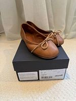 Pair of ballet flats on top of original box, angled view