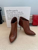 Full view of both ankle boots in front of branded box