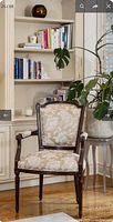 Front angled view of upholstered accent armchair showing carved frame and floral fabric