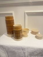 Two tan plaid Aladdin vacuum bottles with lids and stoppers displayed