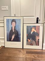 Both framed Modigliani posters leaning against wall