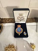 Heraldic brooch and lapel pin in presentation box, additional brooches visible
