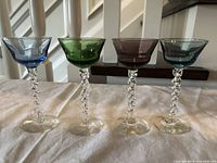 Front view of four colored twisted stem liqueur glasses