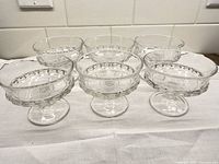 All six clear pressed glass dessert cups displayed