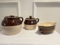 Group shot showing both crocks with lids and stack of four handled dishes