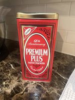 Front of red Premium Plus 60th Anniversary cracker tin