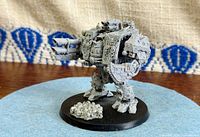 Front left view of fully assembled Chaos Hellbrute miniature on round base with skull pile