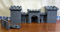 Front view of assembled gatehouse with towers, wall crenellations, separate panels foreground