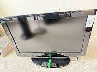 Front view of Samsung 32" HDTV on stand with remote taped to base
