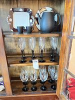 Cabinet shelf showing plates, teapot, cups, flutes and wine glasses