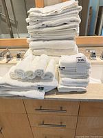 Stack of assorted white towels of various sizes on countertop