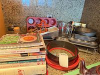 Overall view of cookbooks, bakeware, grinders, trays, racks