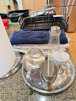 Stainless steel serveware items and glass bottle in front of roasting pan