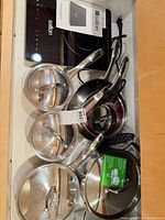 Overview of Salton induction cooktop, power cord, and Duxtop stainless cookware with lids inside drawer