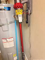 Full view of Dyson Cyclone V10 Motorhead vacuum on wall dock beside water heater