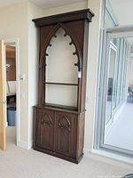 full front view of tall Gothic arch cabinet against wall