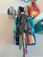 Assorted decorations in blue tote, wrapping paper rolls, gift bags, storage bins