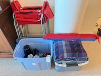 Red folding chairs beside storage bins and blanket