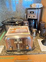 Group shot of toaster, slow cooker, coffee maker, grinder, AeroPress and pitcher on countertop