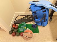 Group shot of all items including wheeled bag, Aquajogger belt, bocce balls, jack, basketball, golf returner, turf mat, racquet cover, cords