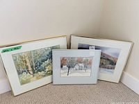Three framed watercolor paintings standing against wall