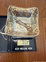 Square pierced dish with two spoons on scale reading 111 g