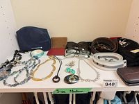 Full group of accessories on shelf including belts, eyewear, wallets, pouches, jewellery