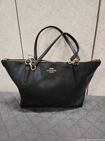 Full view of black Coach leather tote with handles upright