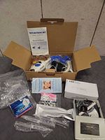 All components laid out: lamp in box, manuals, curing light box, trays, syringes, floss, tips