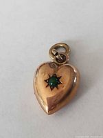 Front view of gold heart pendant showing star-set green stone and jump ring