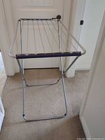 Front angle of silver metal drying rack showing purple end cap and X-frame legs
