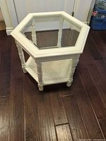 Full view of hexagonal white side table, glass top and perforated shelf visible