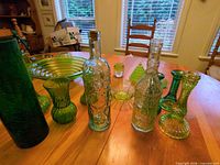 group view of assorted green glass vases, bottles, bowls and candlesticks on table