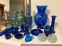 Group of cobalt and aqua glass items including large vase, decanter, candlesticks, tealight holders and bird figurine