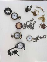 Group shot of five watches, chains and fittings on white surface