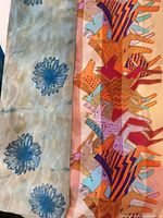 Sheer scarf with blue floral motifs beside multicolor horse-print scarf