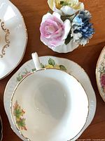 Cup and saucer with maple leaf motif beside porcelain floral ornament
