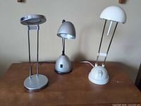 All three desk lamps on tabletop showing overall designs and finishes