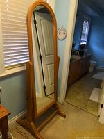 Front view of full-length cheval mirror showing arch-top wood frame and glass panel