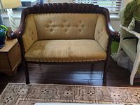 Front view of loveseat showing wood frame, tufted upholstery, nailhead trim